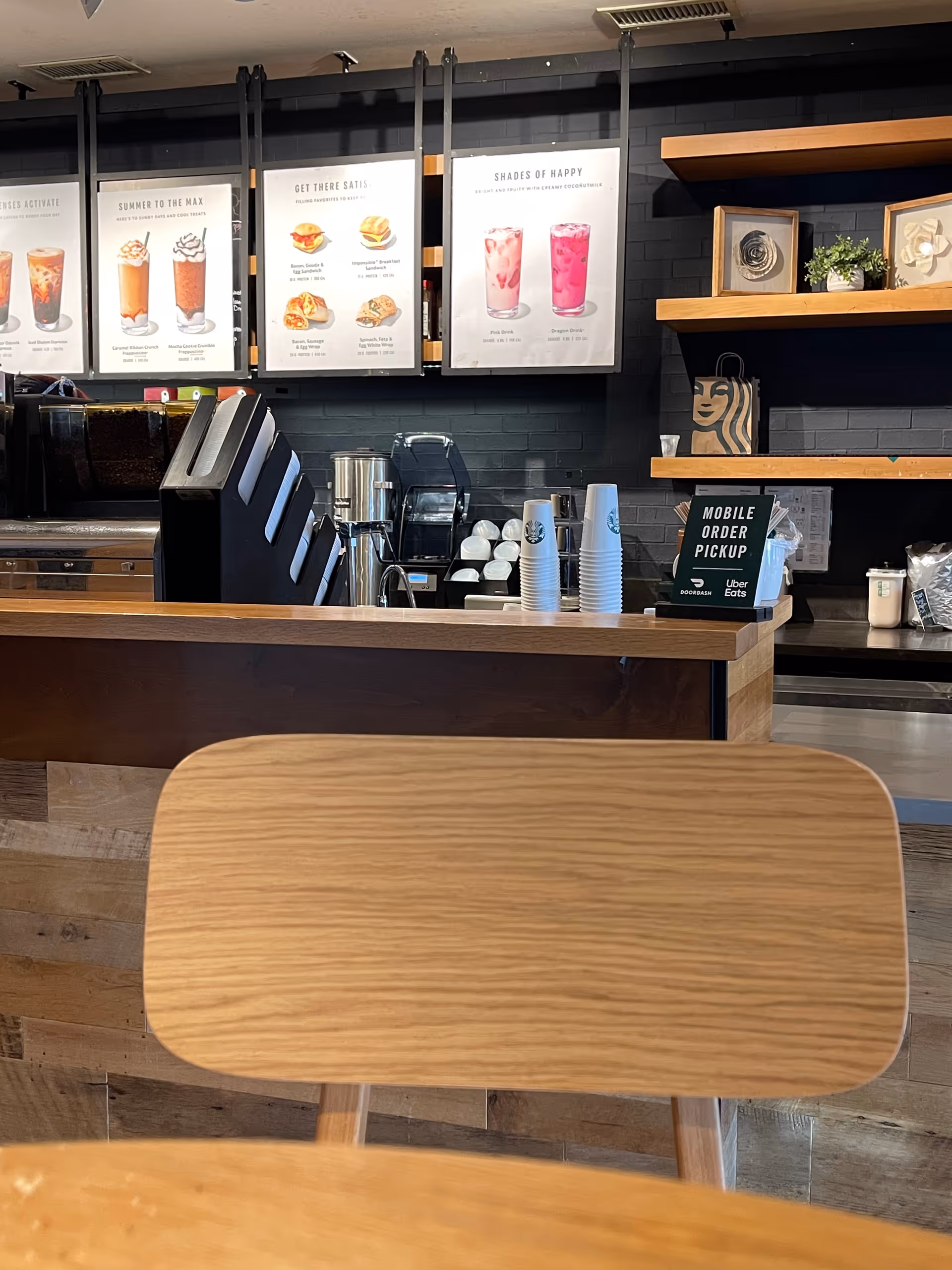 Cafe counter with drink menus, cups, and wooden seating inside a senior living facility.