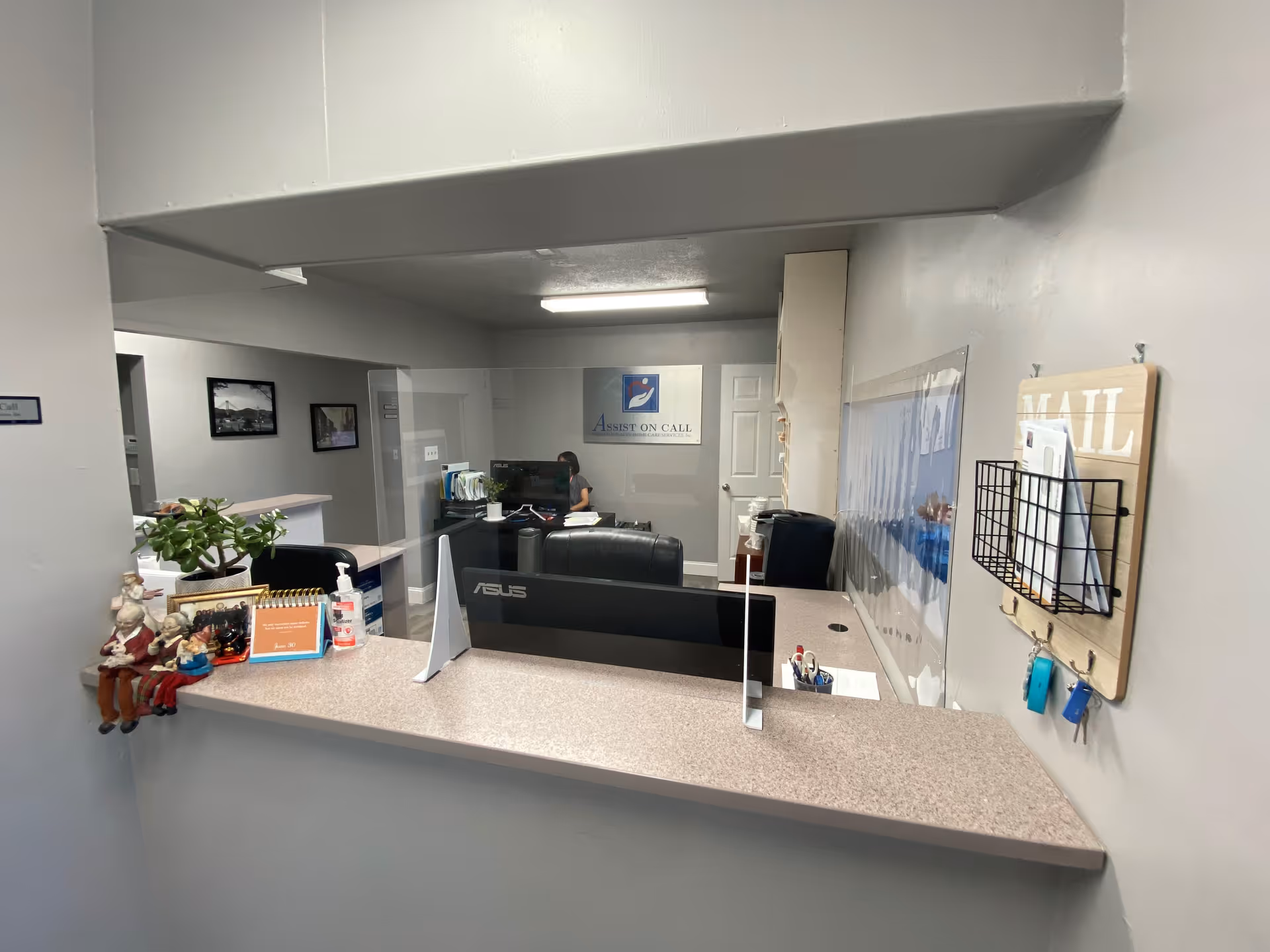 Reception area with front desk, computer monitor, and staff member behind the counter