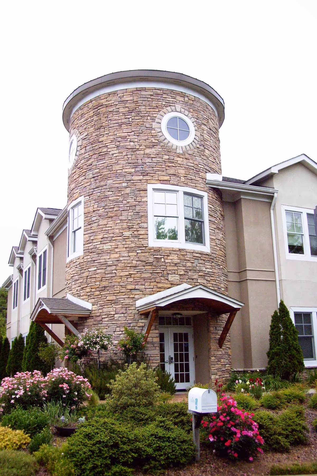 Stone cylindrical tower and front entrance of a senior living building with landscaped garden.