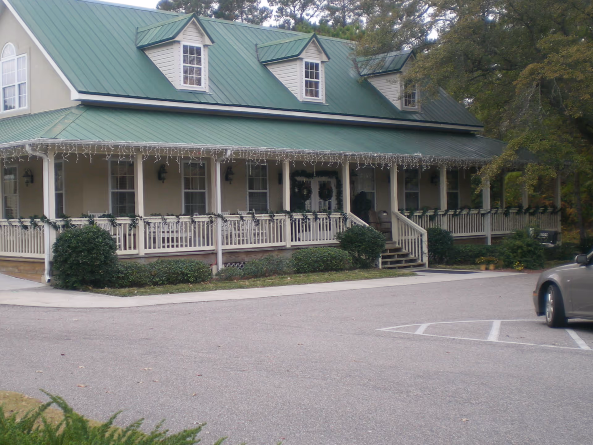 Green-roofed senior living facility with a wraparound porch and string lights