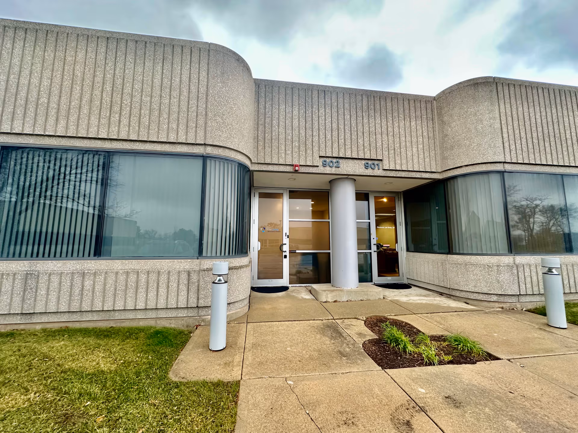 Exterior view of a curved concrete building with glass entrance doors.