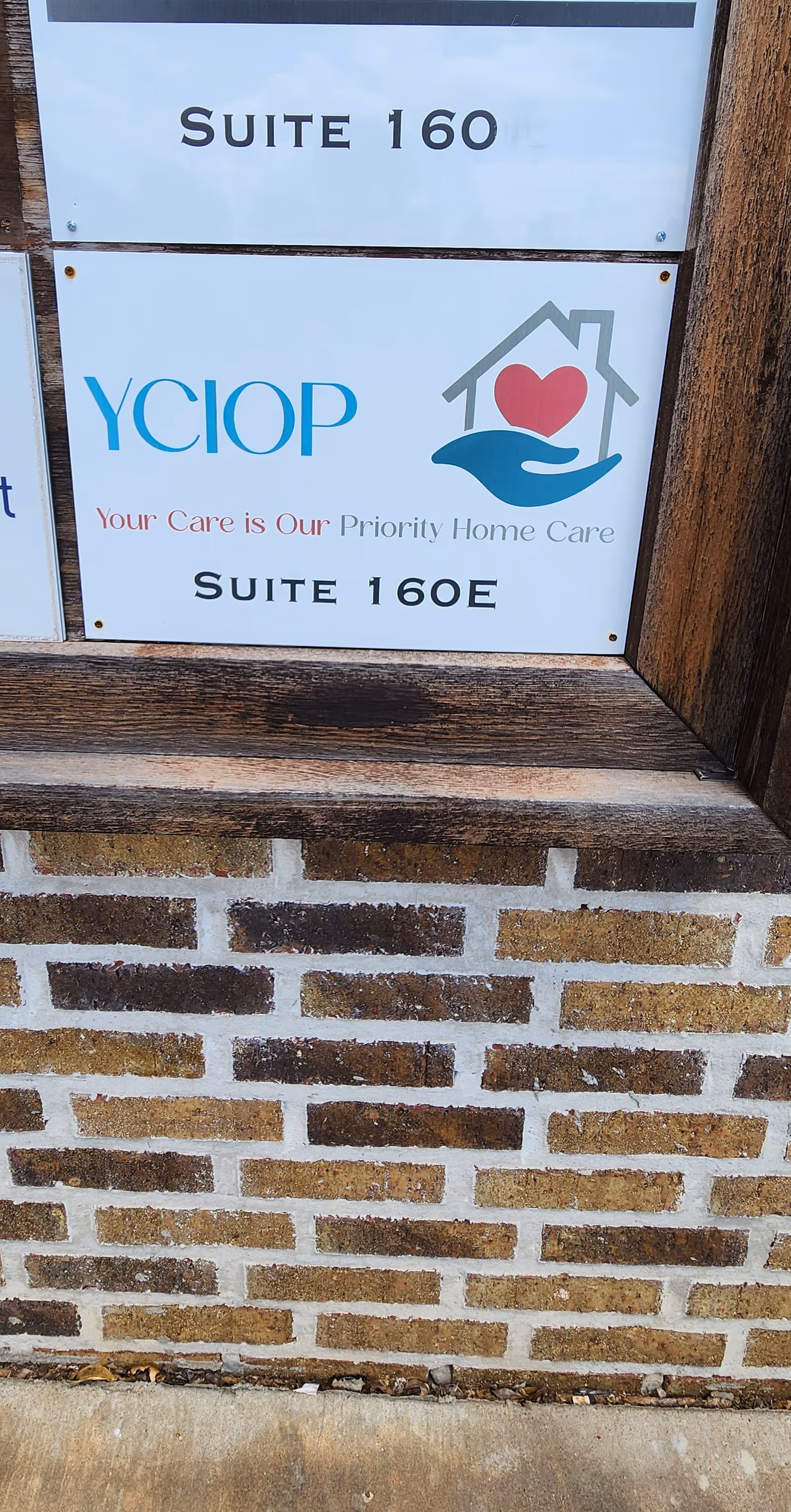 Sign for YCIOP Home Care Suite 160 on brick exterior wall.