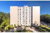 Front view of Deering Pavilion, a multi-story beige senior living building with surrounding trees.