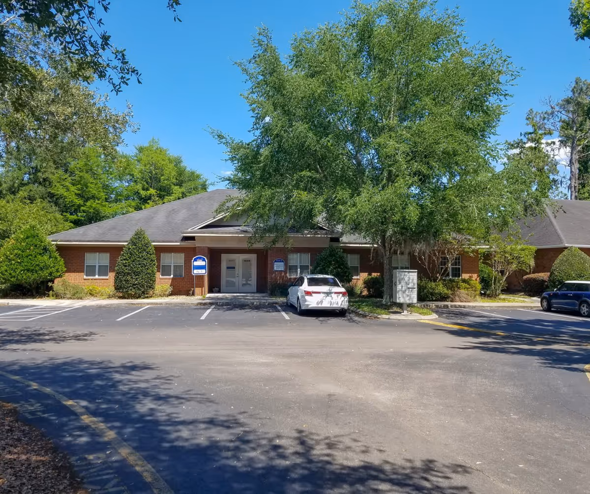 Exterior view of Brooks Rehabilitation Home Health Gainesville building with trees and a parking lot.