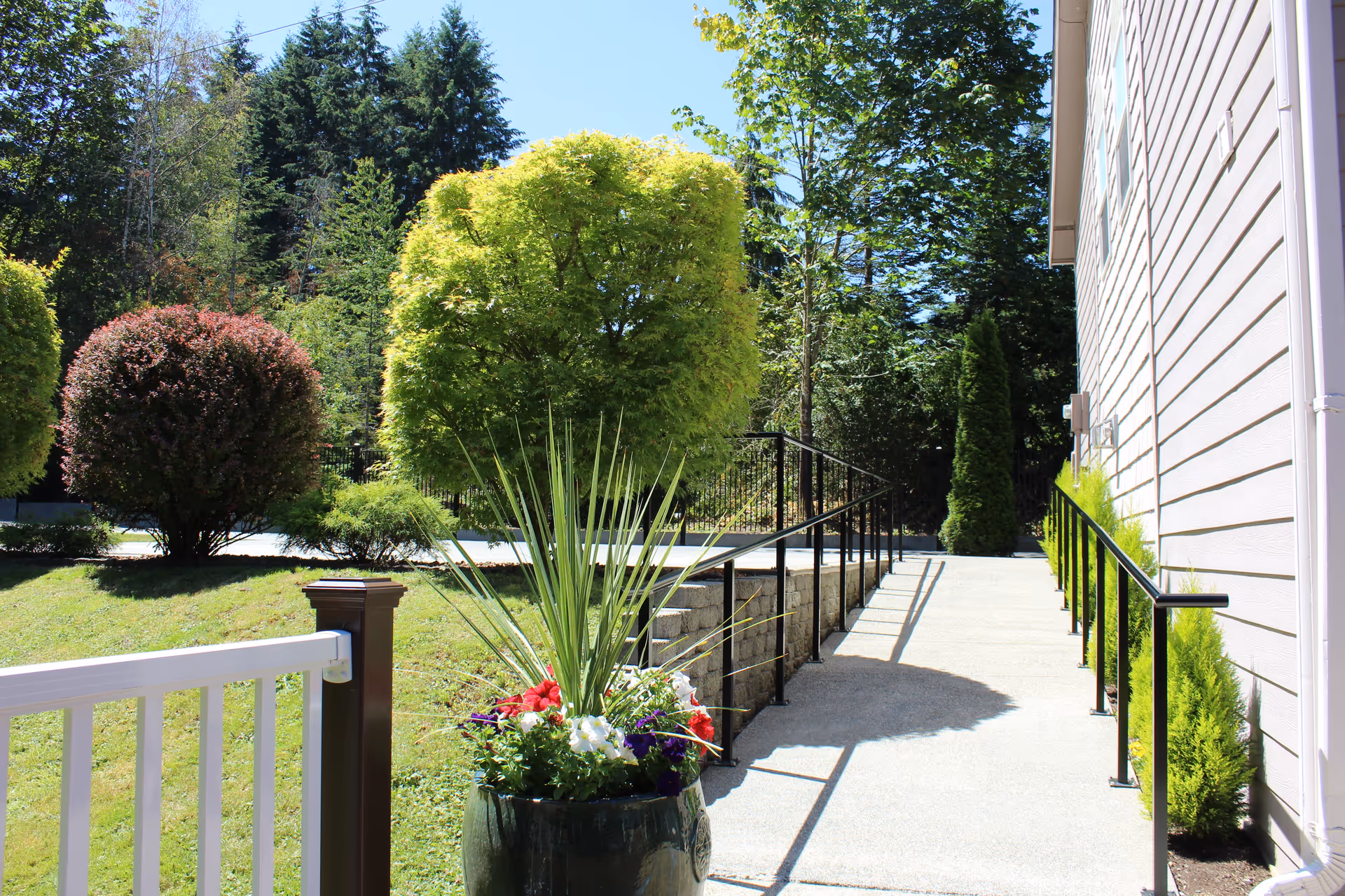 Exterior walkway beside Daniela's Adult Home Care with ramp, railing, and planters.