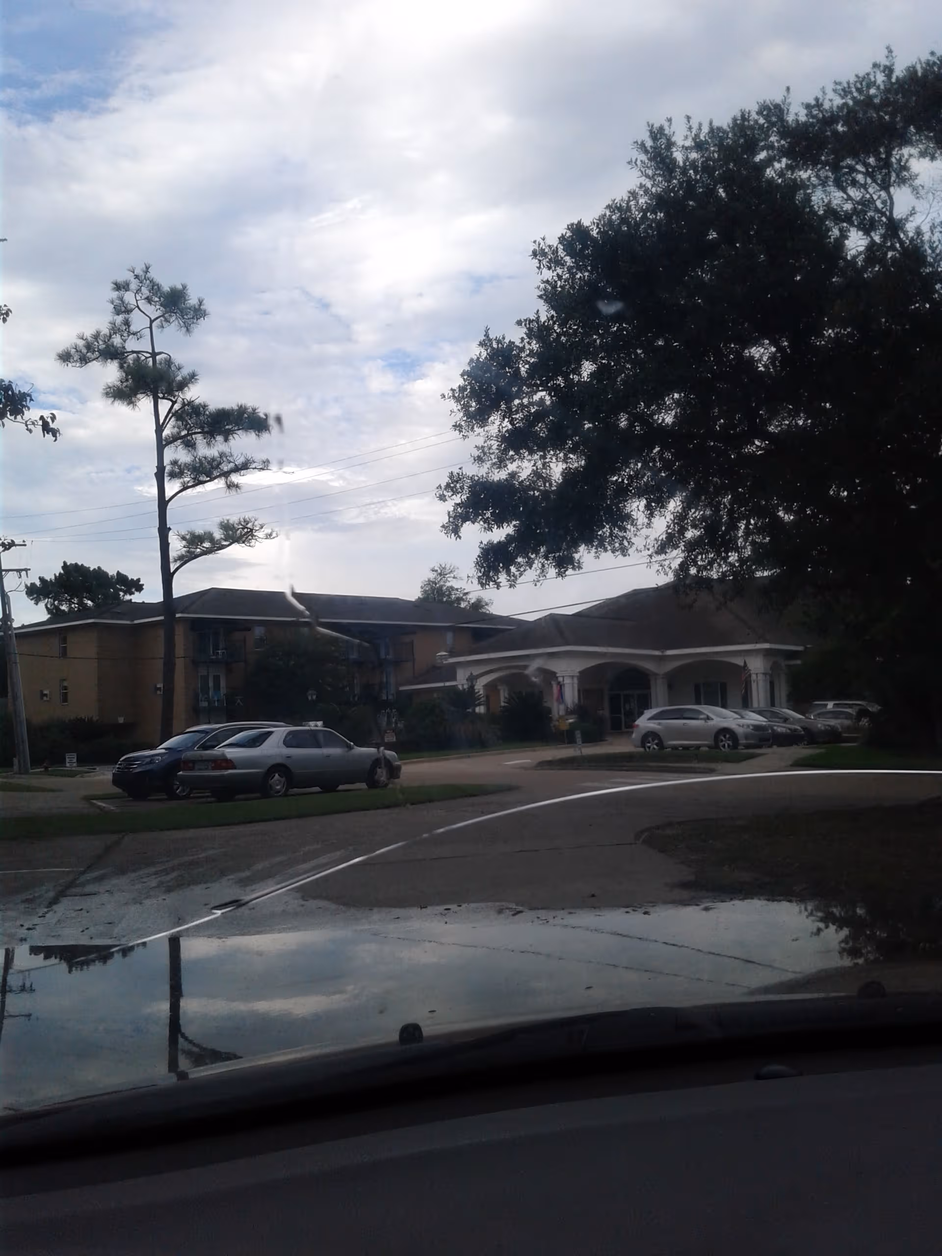 Front exterior view of a retirement center with a curved entry and parked cars.