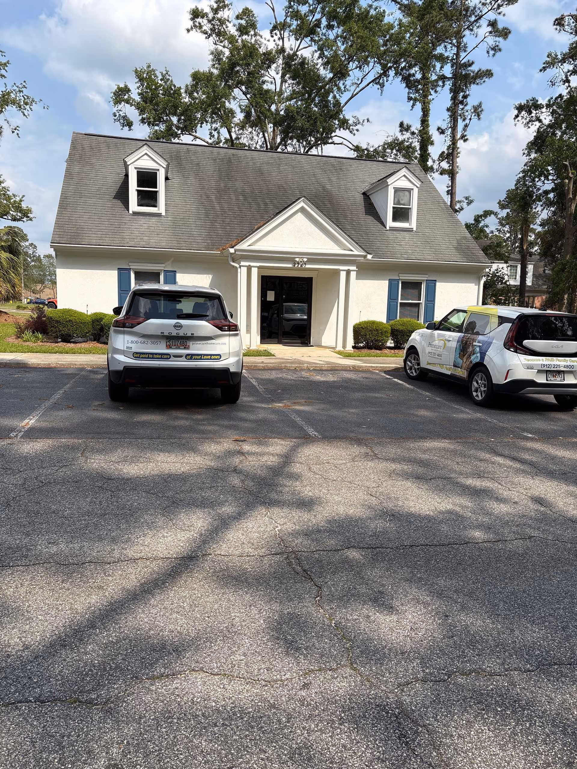 Front view of Primecare Home Care Services building with blue shutters and parked cars.