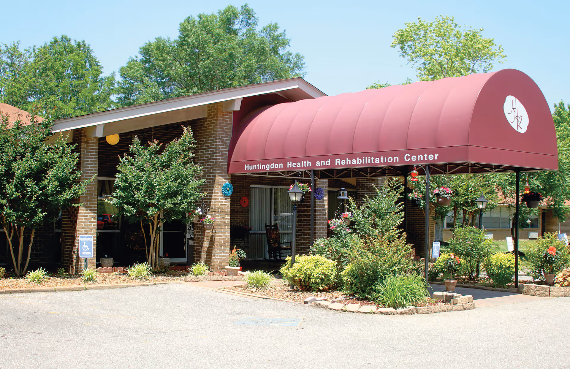 Front view of Huntingdon Health and Rehabilitation Center with maroon awning entrance and landscaping.
