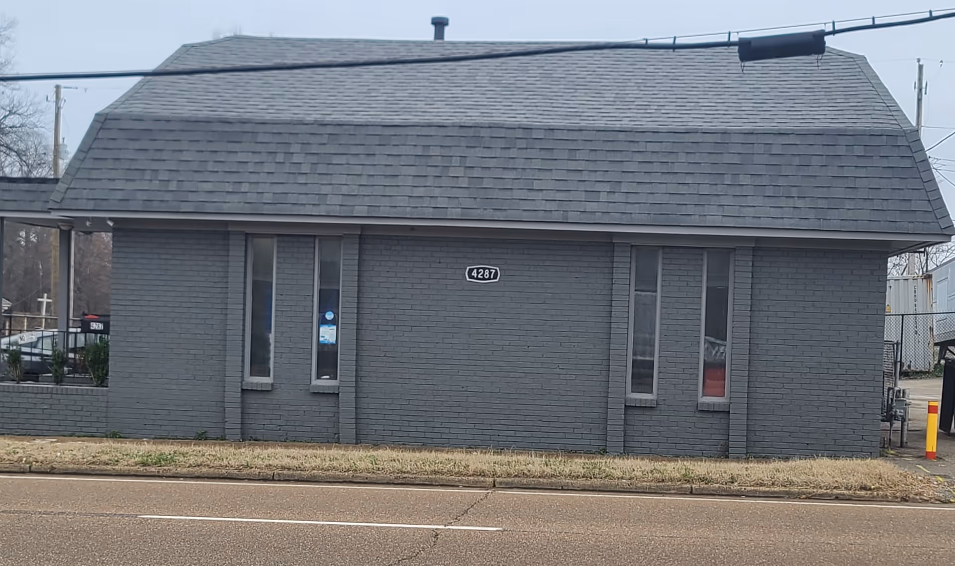 Gray brick senior living facility with a sloped roof and small windows facing the street