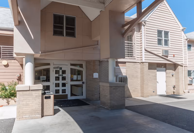 Front entrance of Grand Villa Assisted Living building with brick columns and glass doors.