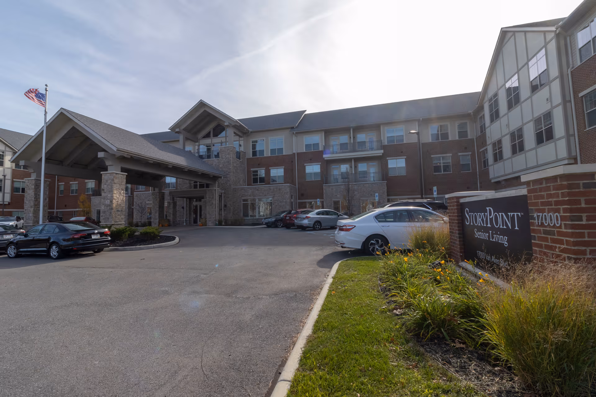 Exterior view of StoryPoint Shaker Heights senior living campus with parked cars at entrance.