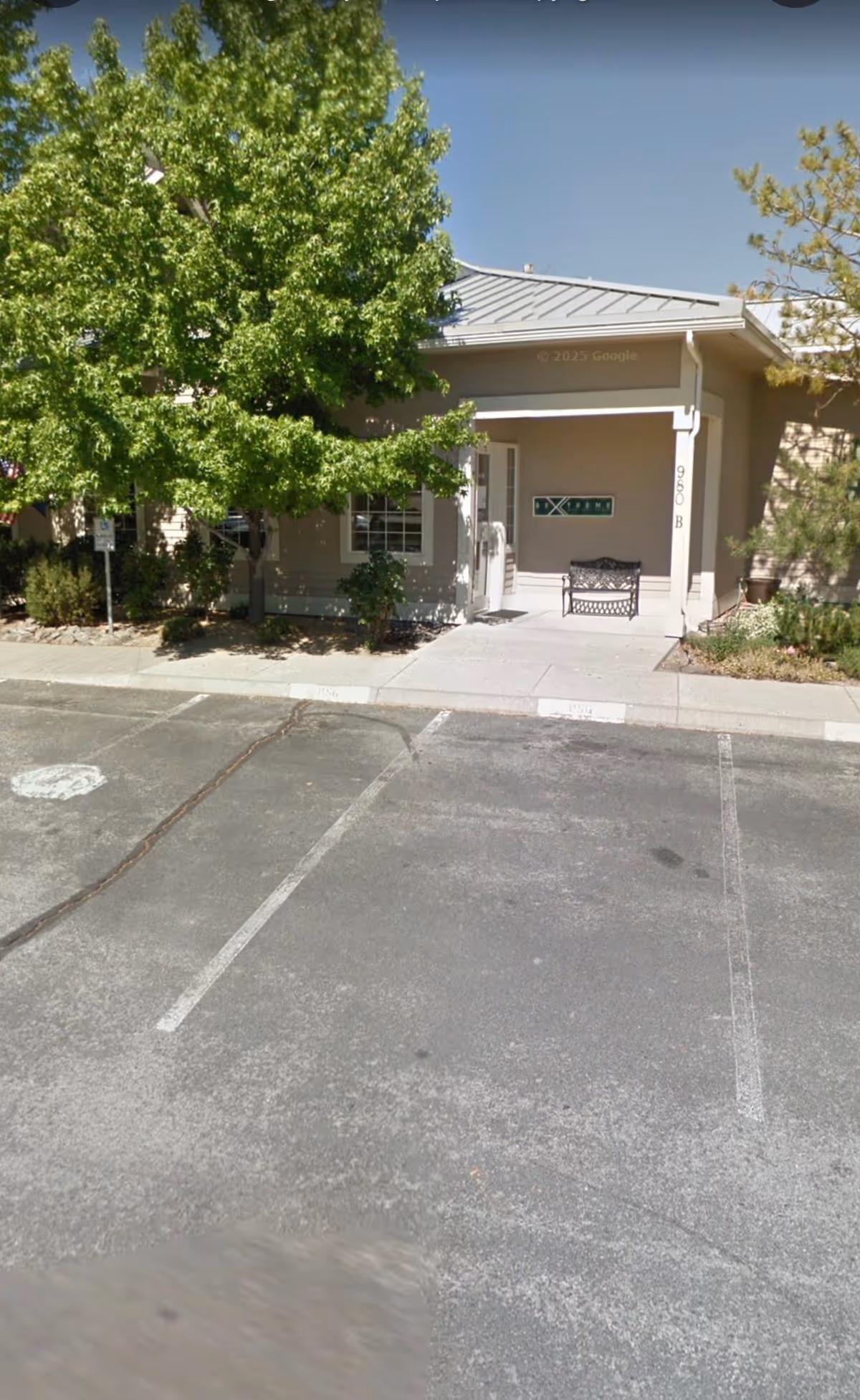Exterior view of a senior living facility entrance with a bench and trees