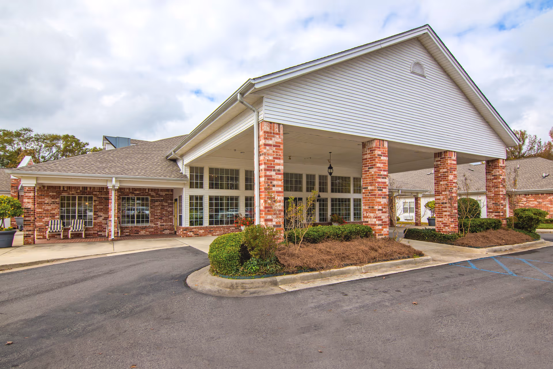 A brick senior living facility with a large covered entrance and brick columns.