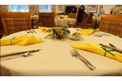Dining table set with yellow napkins and a floral centerpiece in a senior living dining room.