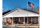 Front view of The Waters of Clifty Falls facility, brick building with flagpole and covered porch.
