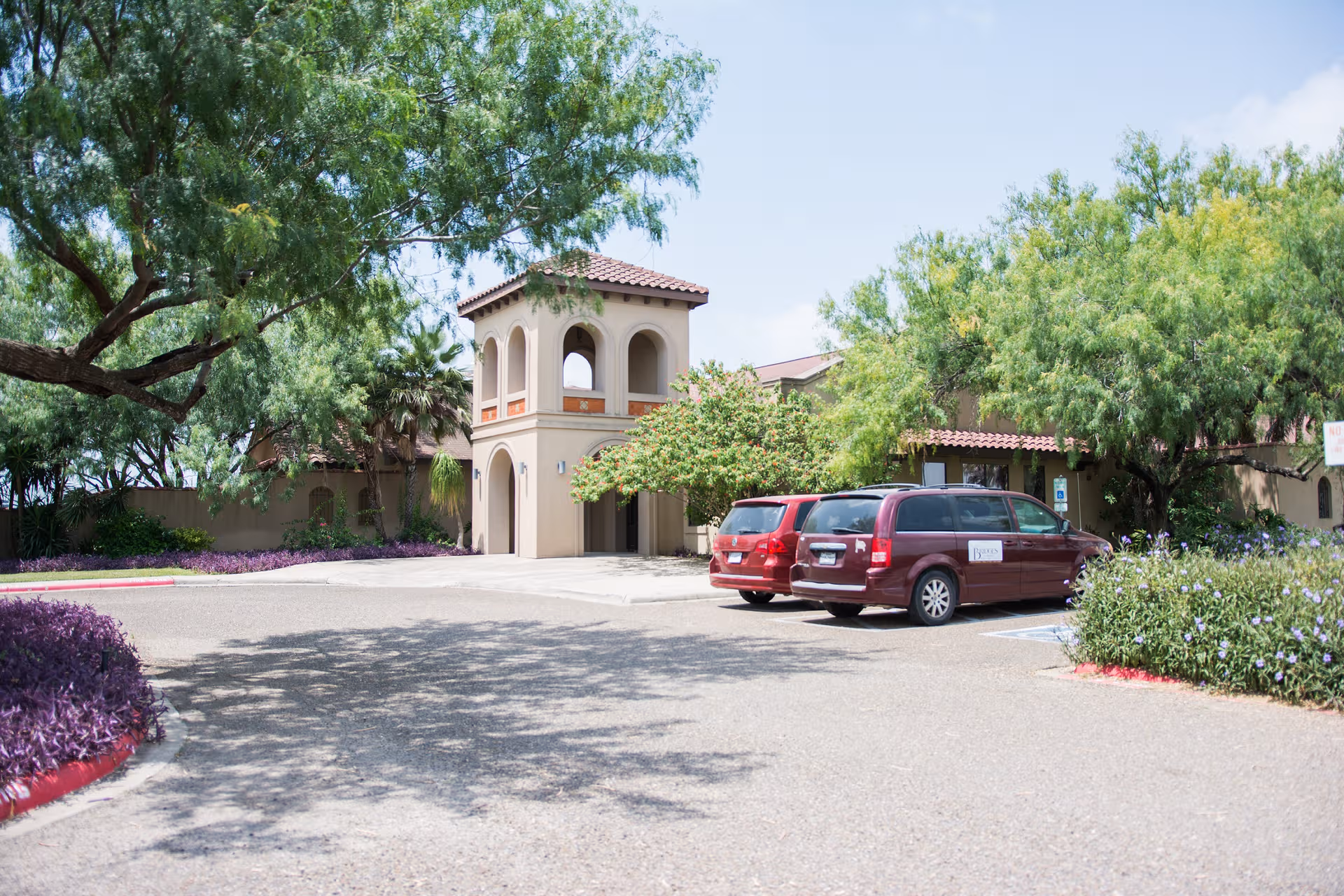 Exterior view of Bridges at Mission Assisted Living Homes with a beige building and parked vans.