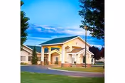 Front view of Cheney Assisted Living building with yellow exterior, green lawn, and blue sky.