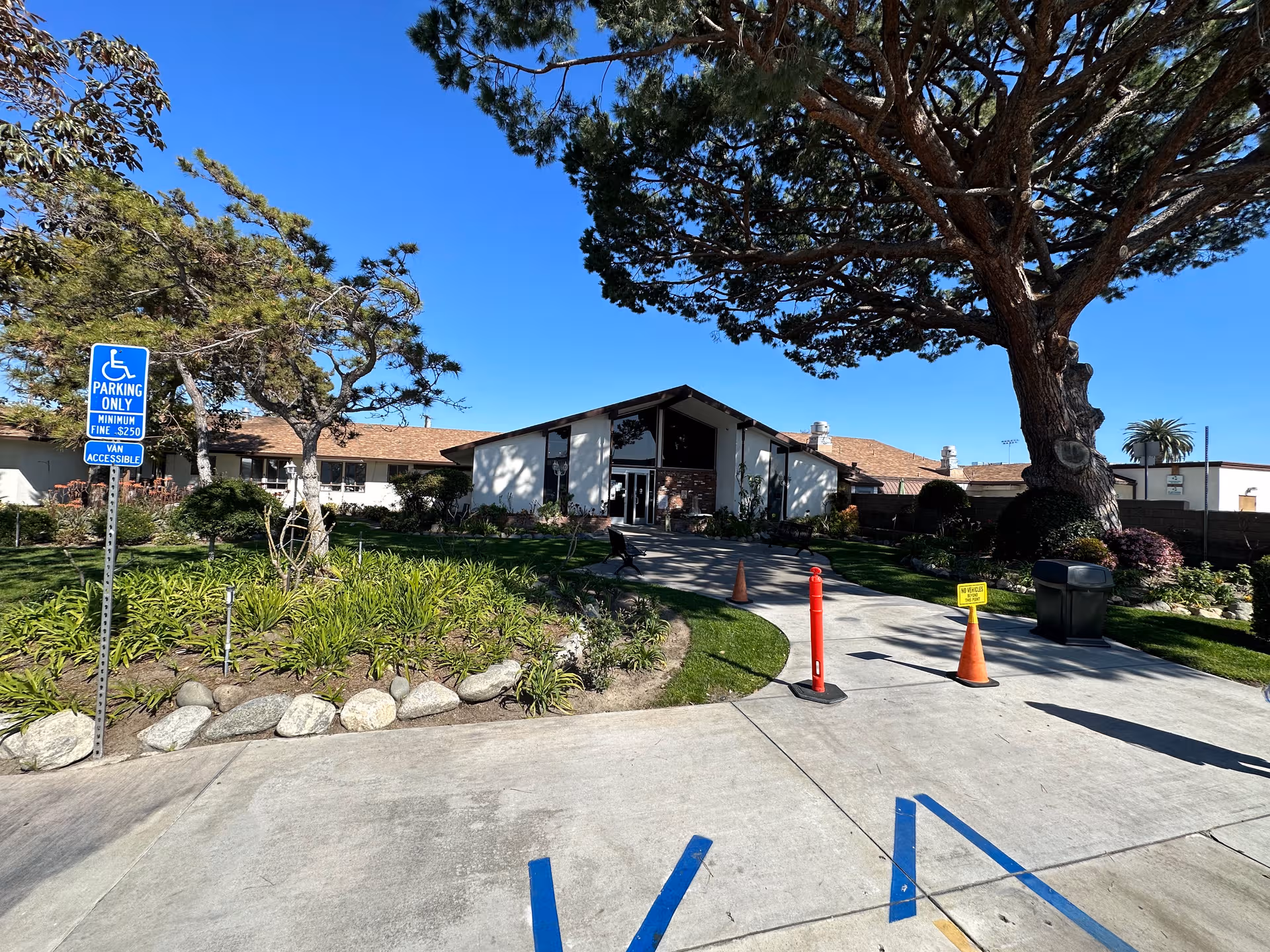 Front view of Pacific Haven facility entrance with driveway, landscaping, and a large tree.
