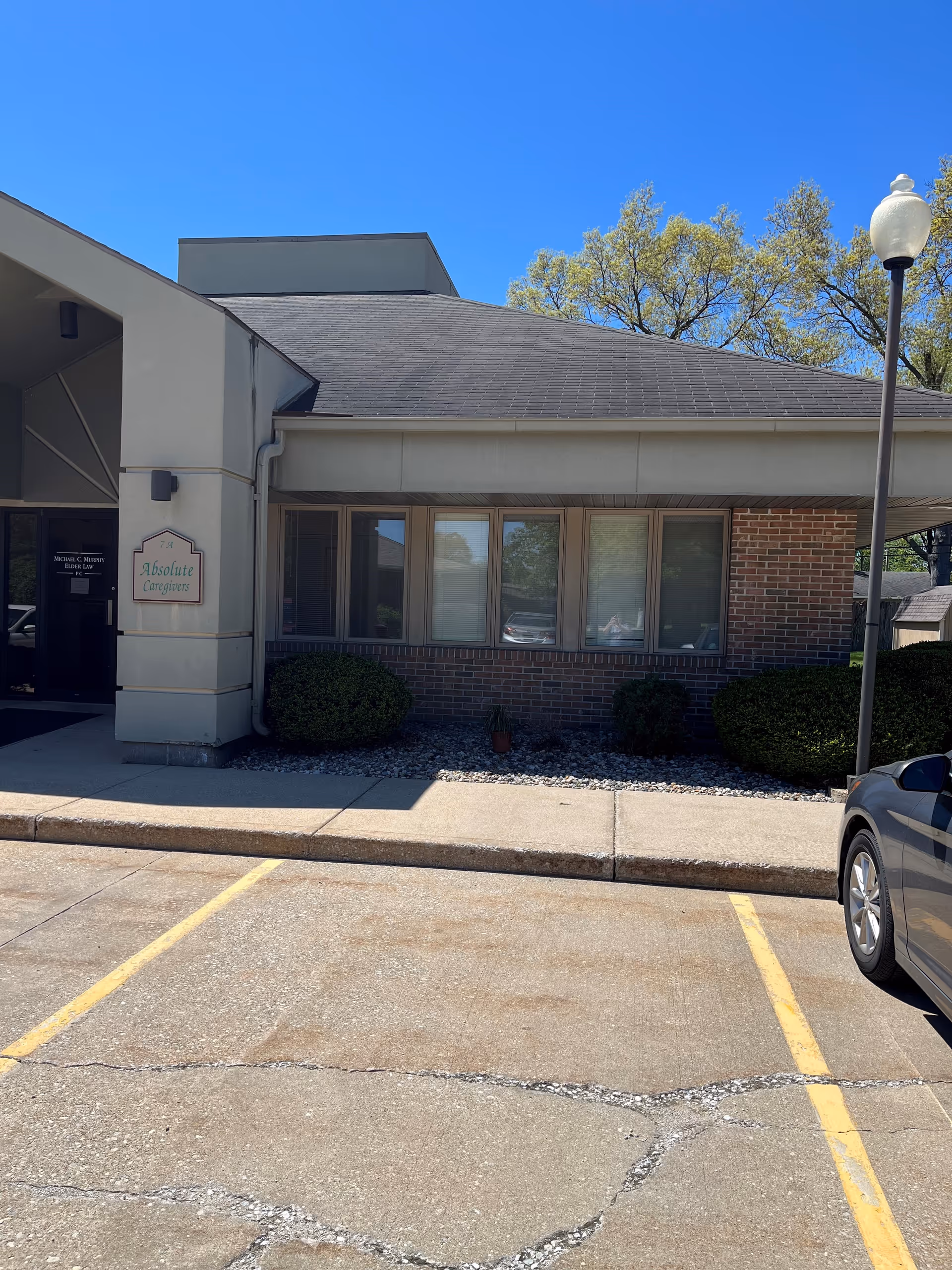 Exterior view of Absolute Caregivers facility entrance with sign and parked car.