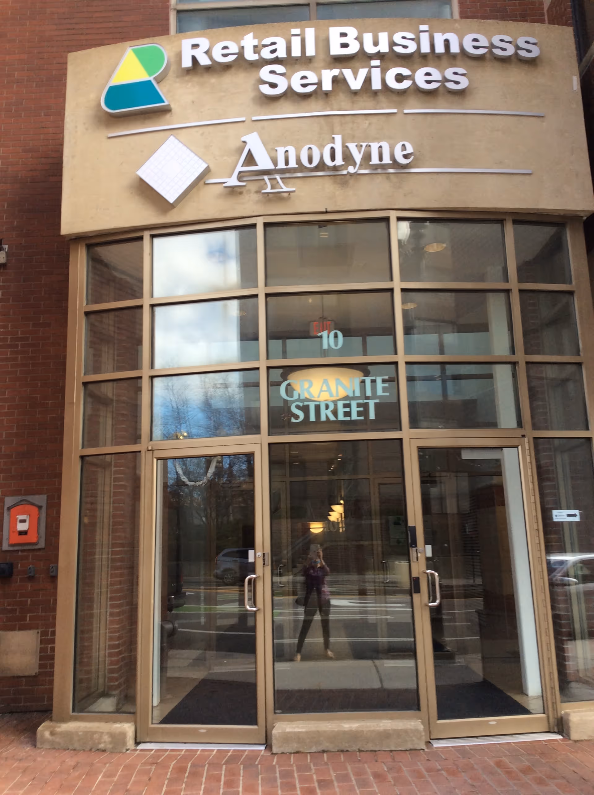 Brick-faced building exterior with large signage for Retail Business Services and Anodyne above glass doors.