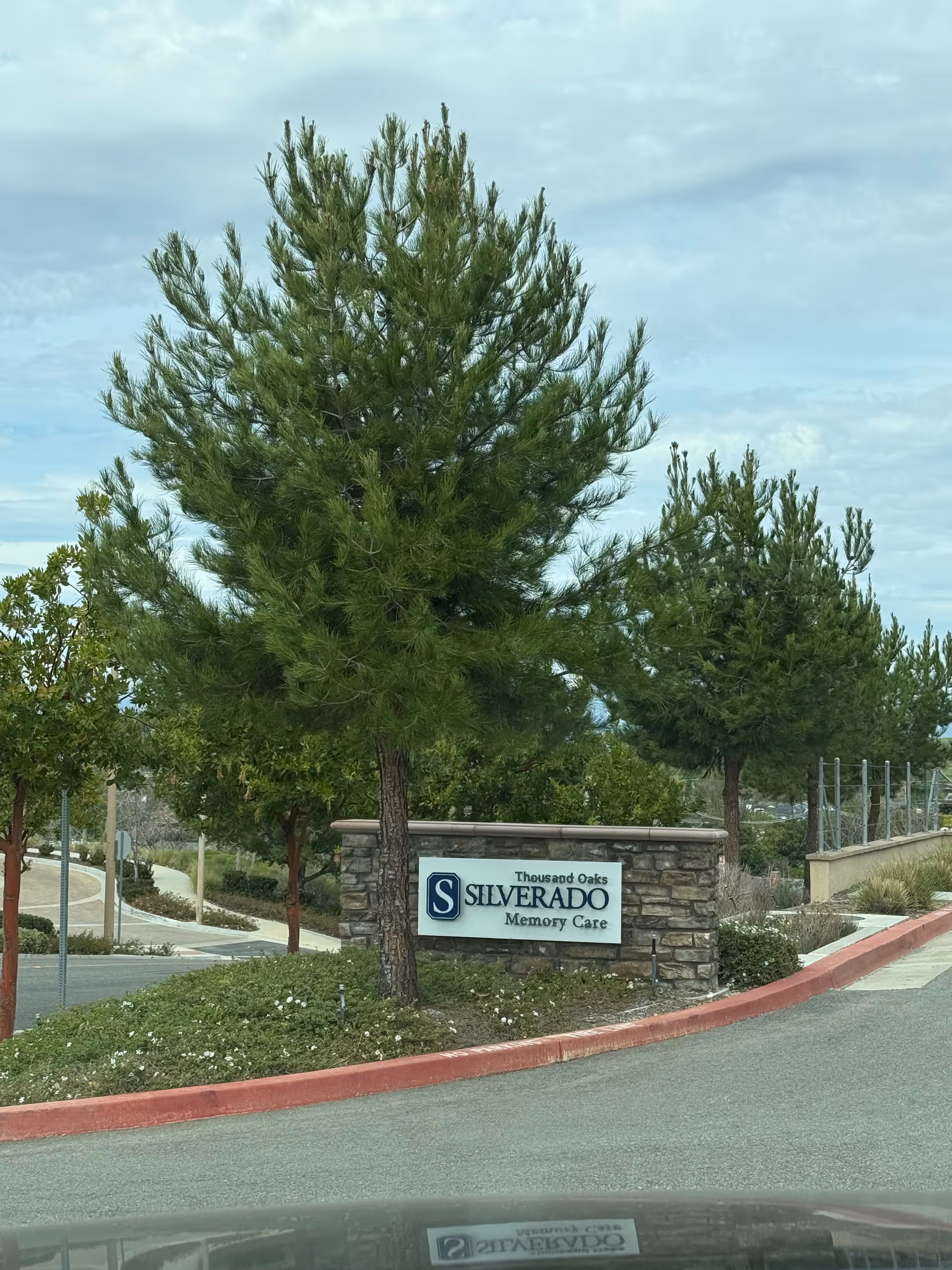 Stone entrance sign for Silverado Memory Care in Thousand Oaks, framed by trees.
