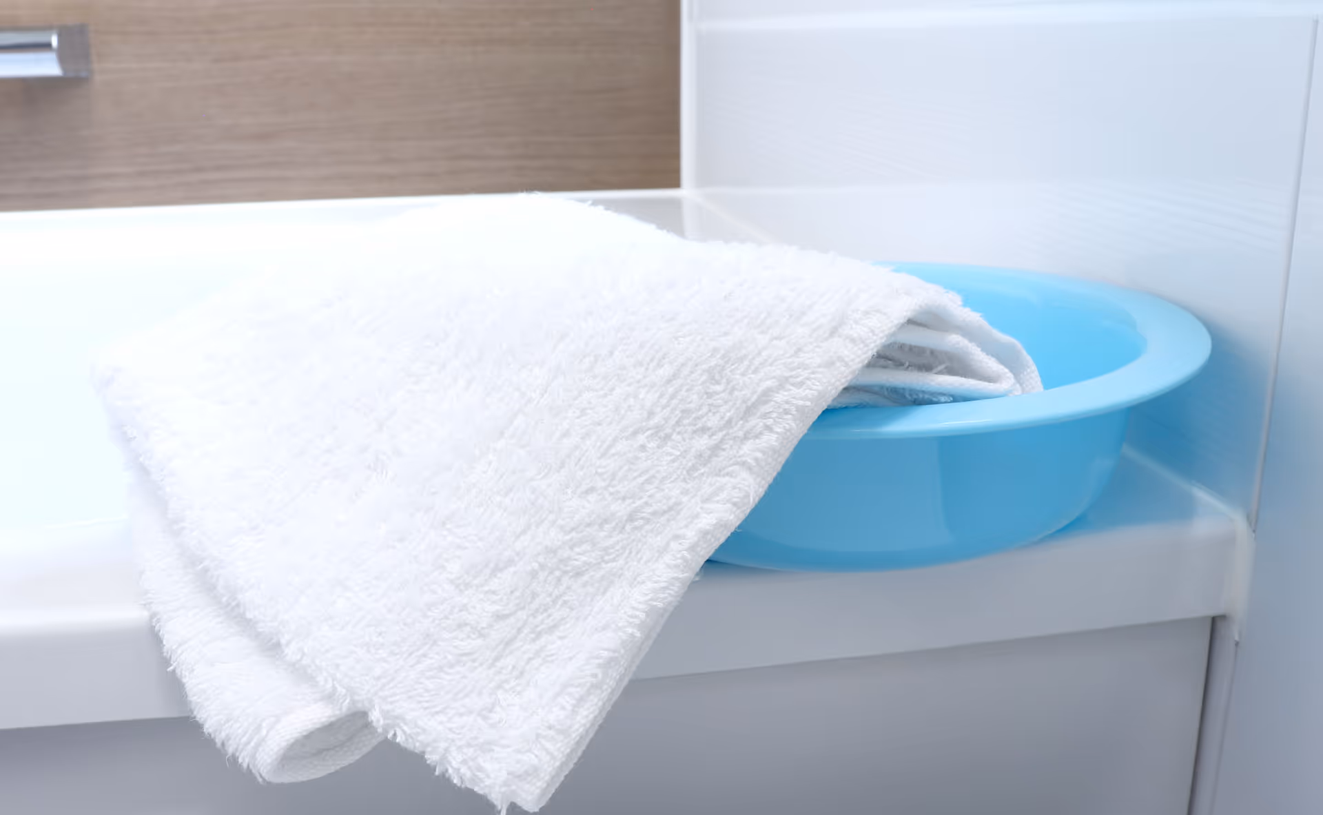 Close-up of a white towel draped over a blue basin on a bathroom counter.