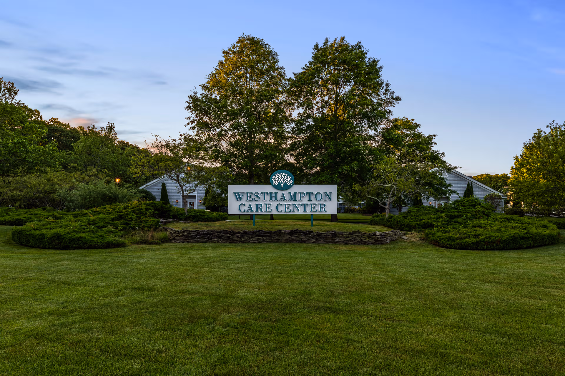 Grassy front lawn with a Westhampton Care Center sign and surrounding trees.