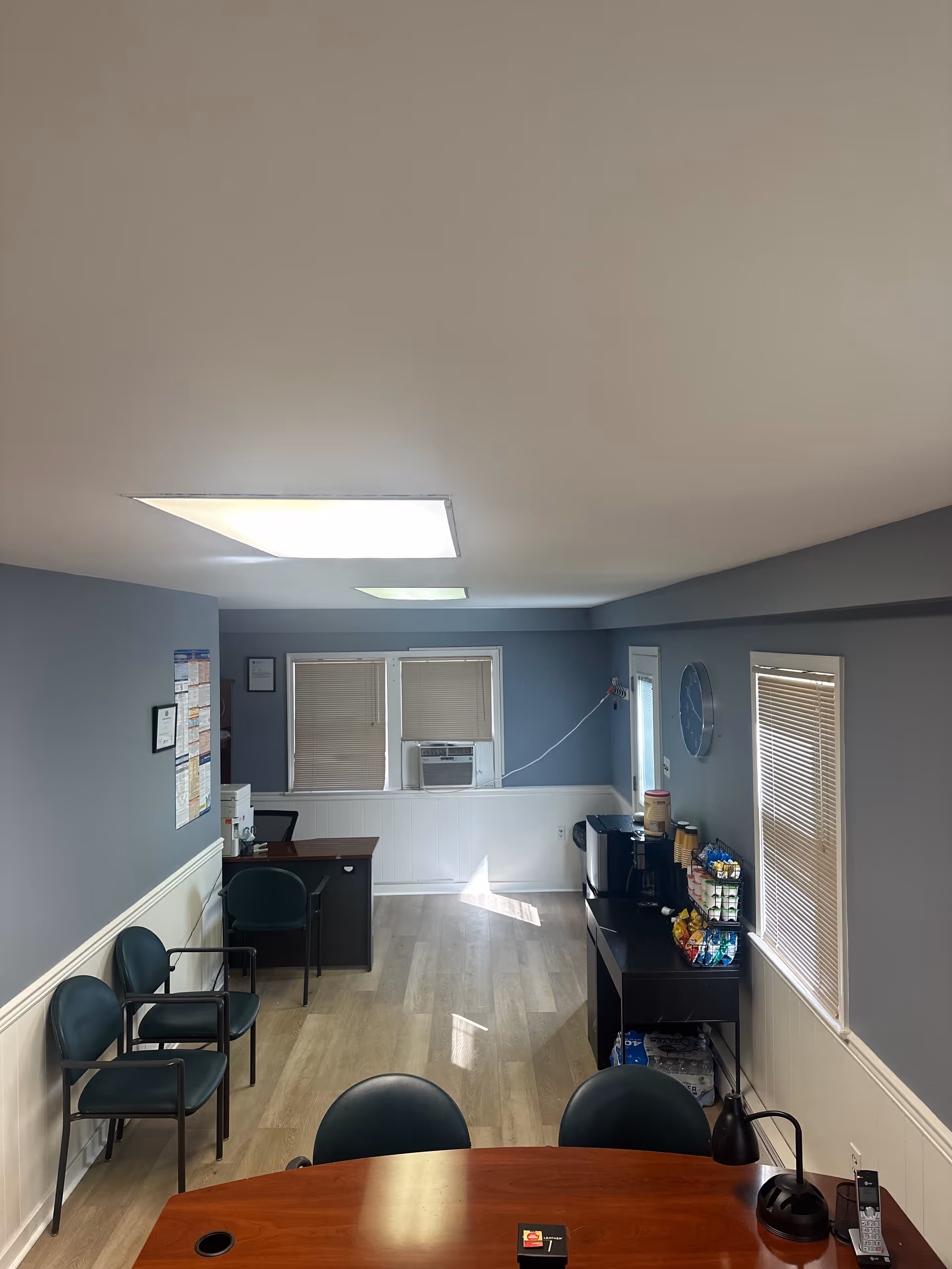 Interior common area with round table, chairs, and coffee station in a senior facility.