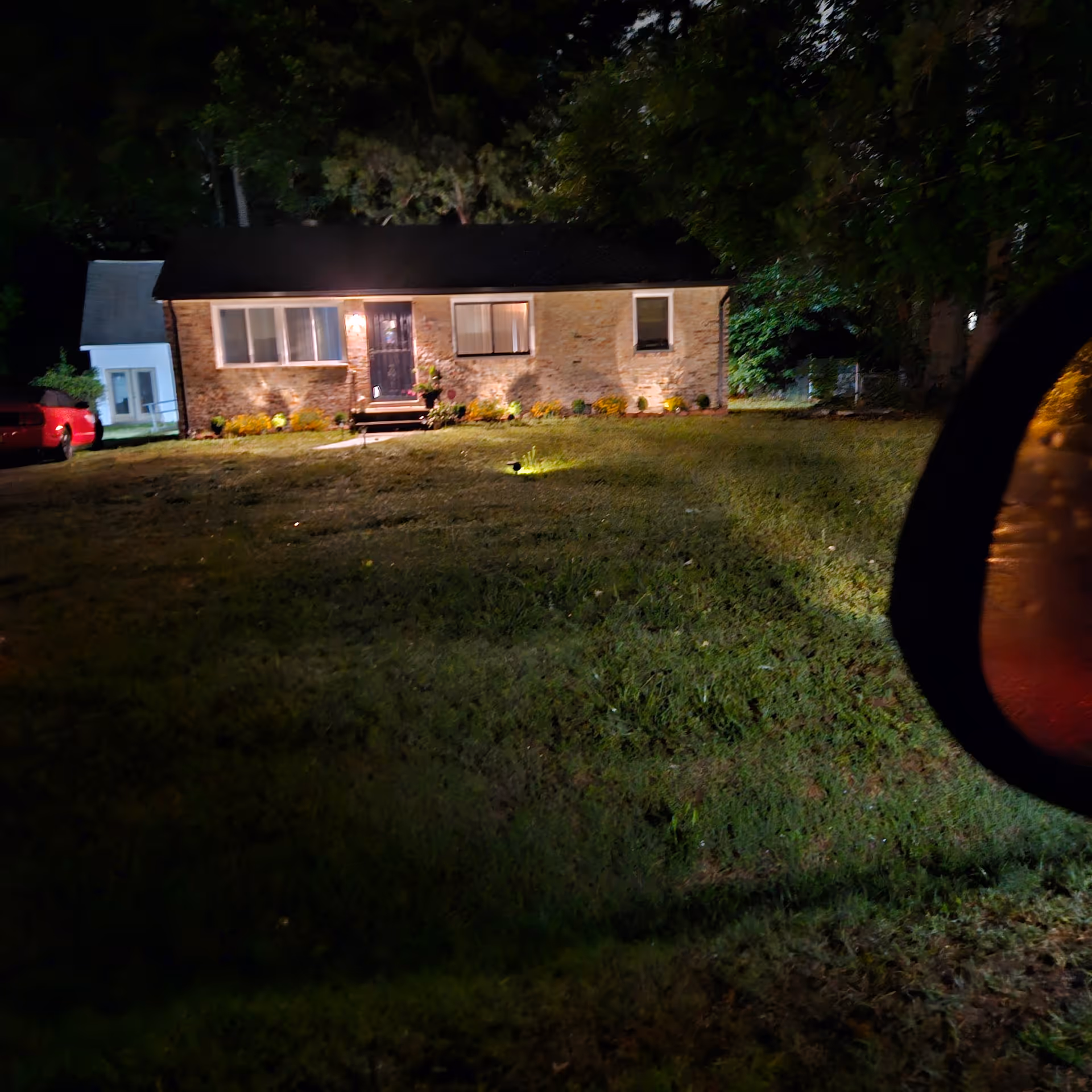 Nighttime exterior of a brick senior care facility with a lit entrance and front lawn.