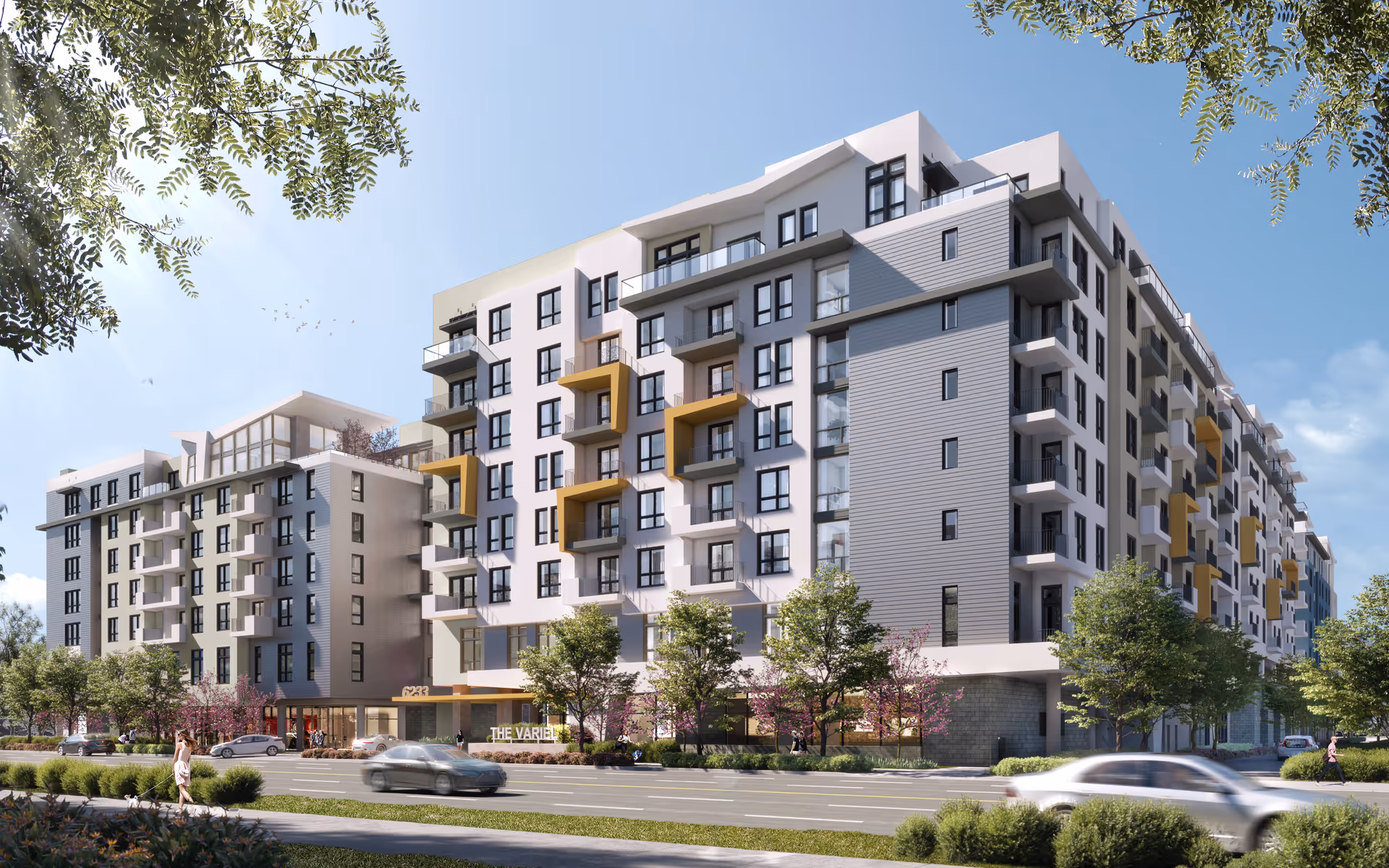 Modern multi-story senior living building with balconies along a tree-lined street.