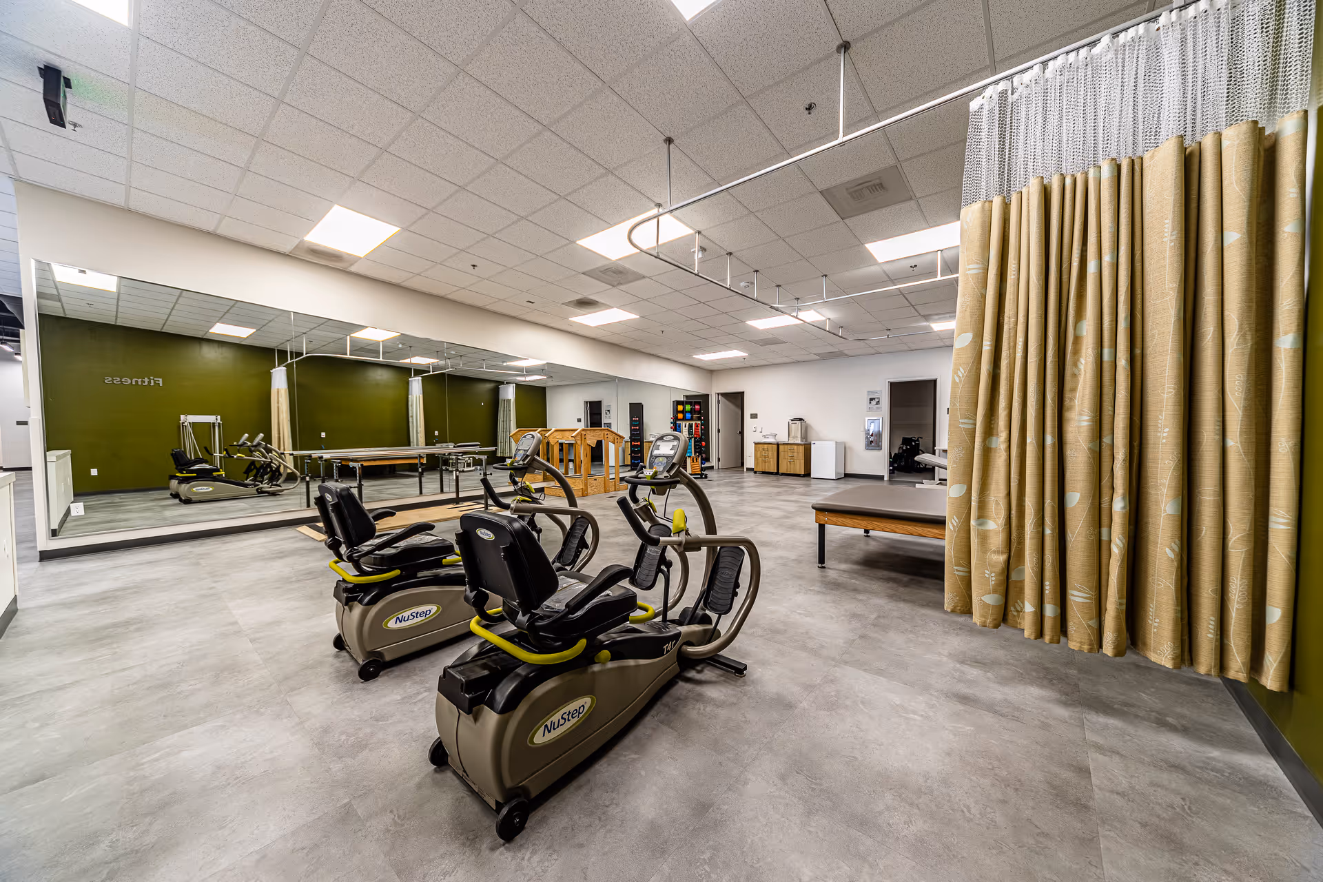 Exercise room in a senior living facility with NuStep machines and mirrors.