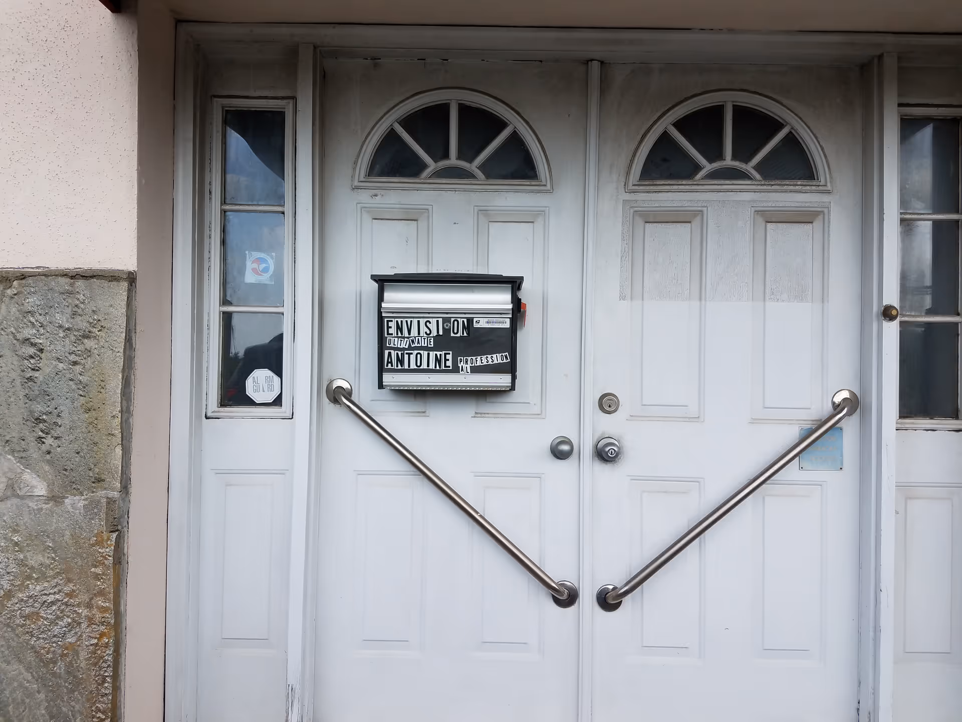 Front entrance with double white doors, arched transom windows, and metal handrails.