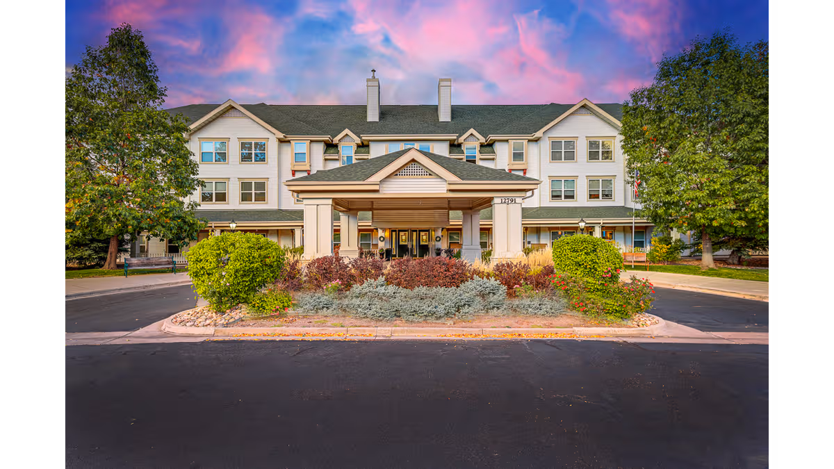 Exterior view of Woodlake Legacy Senior Living building with entrance canopy and manicured landscaping.