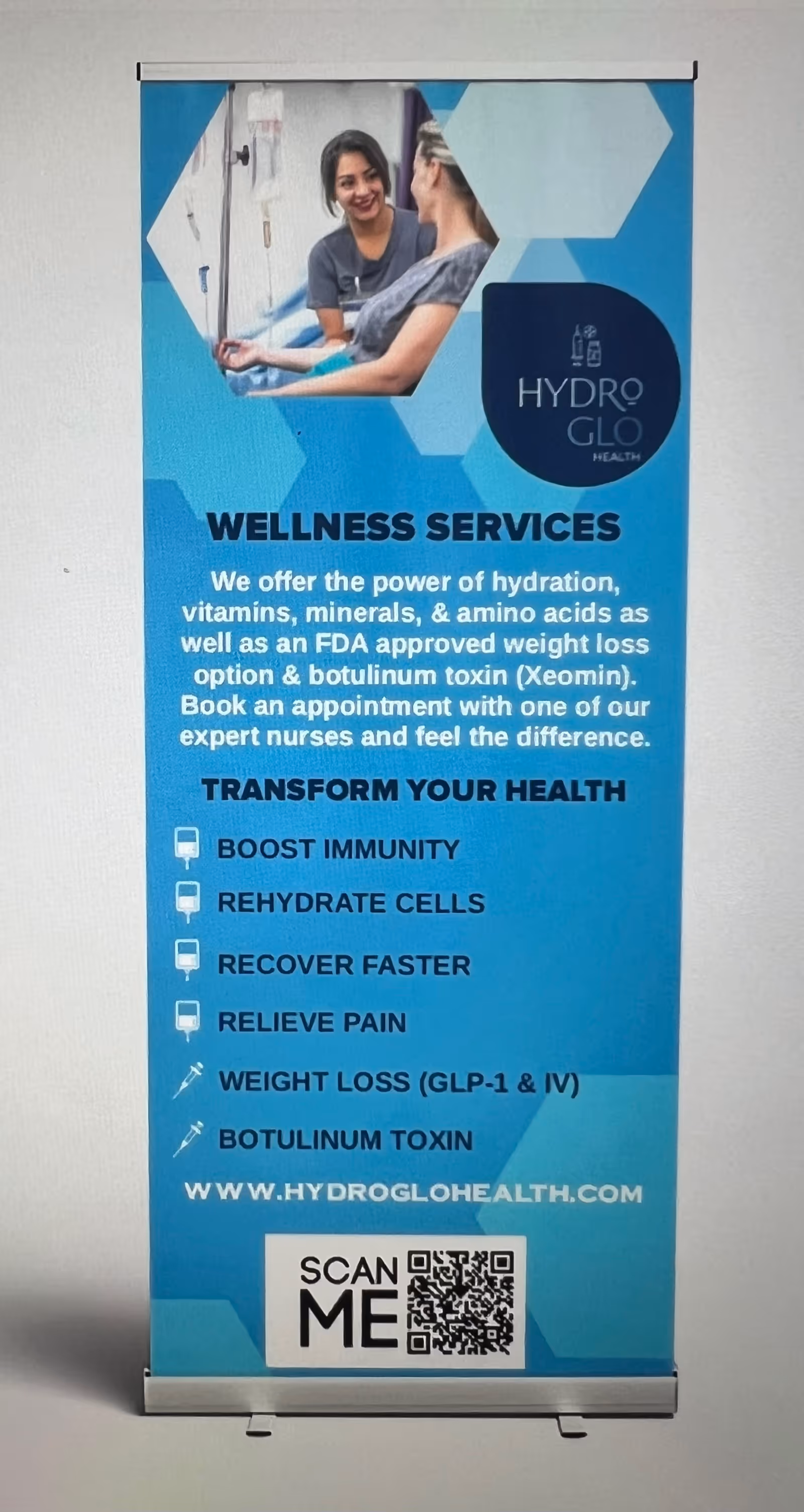 A tall wellness banner stands indoors, showing a nurse with a patient image and blue graphics.