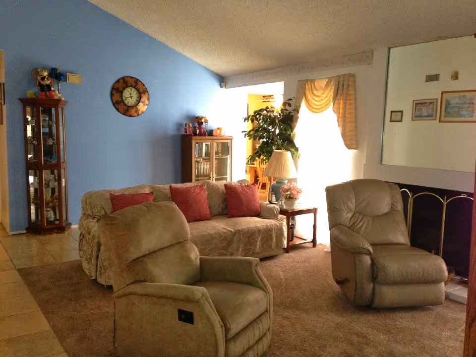 Cozy living room with beige furniture, blue wall, and a decorative cabinet.