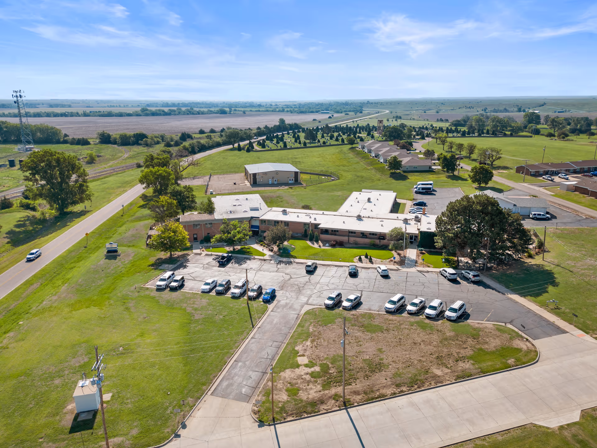 Aerial view of a single-story senior living facility with parking and green surroundings.