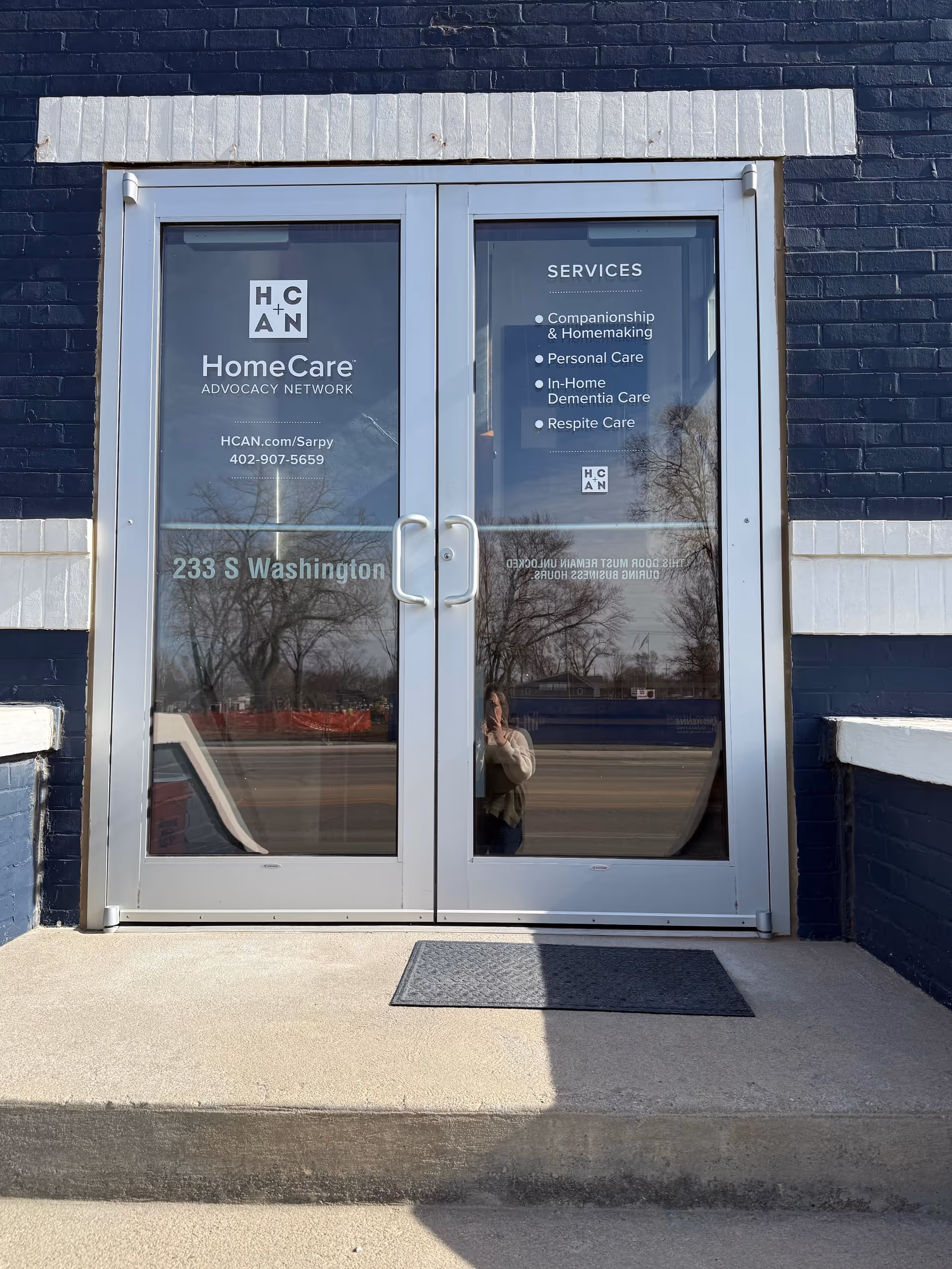 Double glass doors with HomeCare Advocacy Network signage on a dark brick exterior.