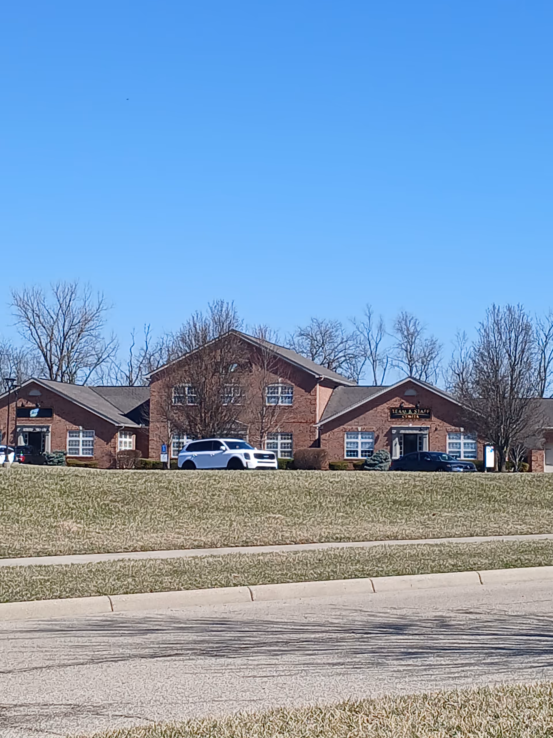 Brick exterior of Ohio's Hospice building with parked cars in front and leafless trees.