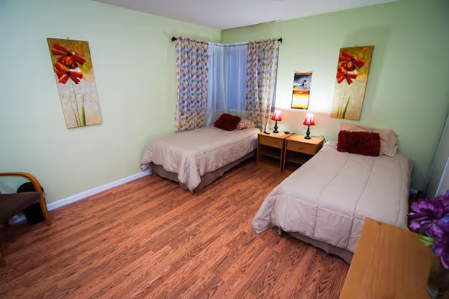 Bedroom at Genesis Care Home for Elderly II with two beds, nightstands, and lamps.