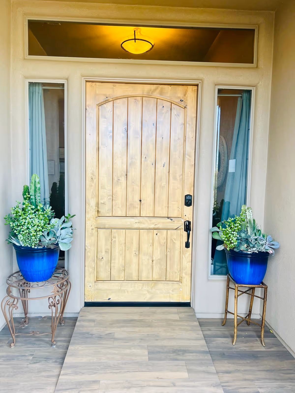 Front entrance of Fountain Hills Manor with wooden door and blue potted plants.