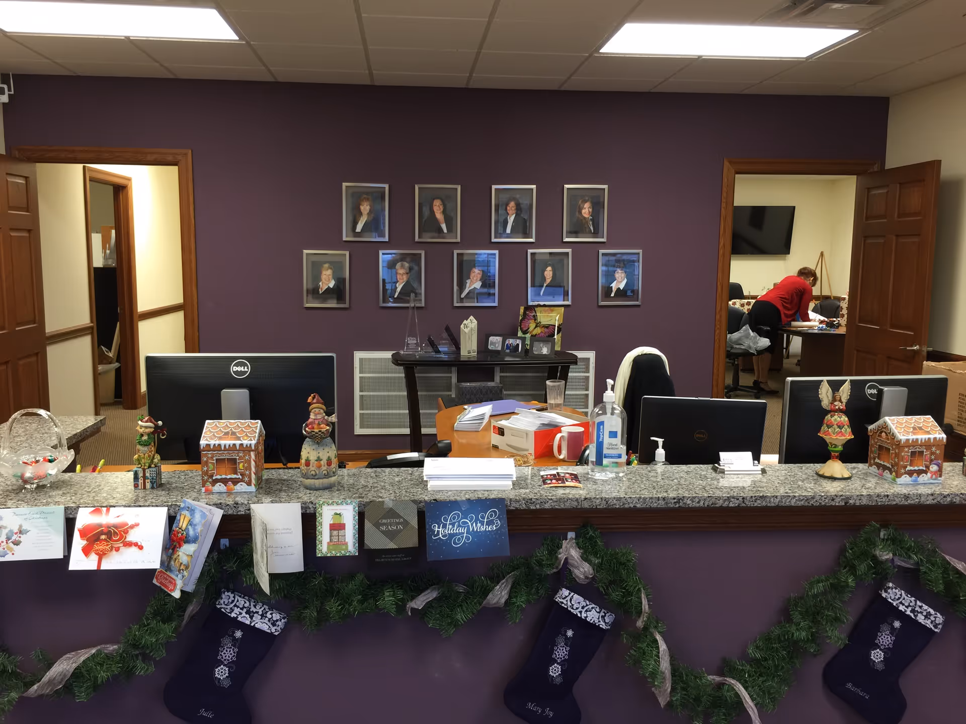 Reception counter in a purple-walled lobby with staff portraits and festive decorations.