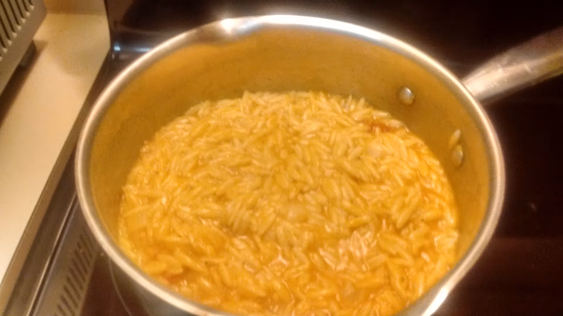 Large pot of pasta simmering in sauce on a stove in a kitchen.