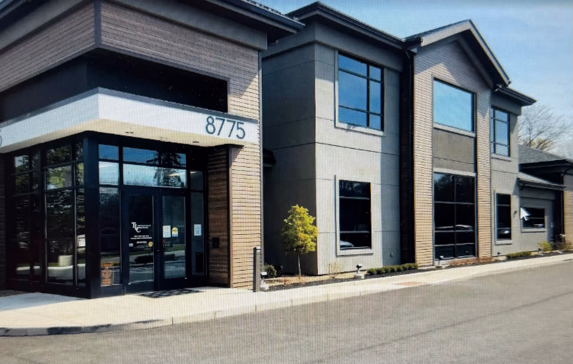 Exterior of TLC Home Healthcare facility with glass doors and brick facade.