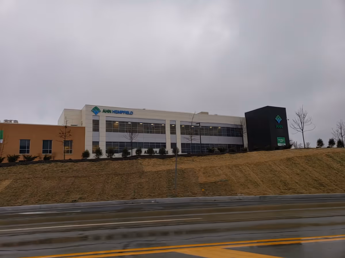 Exterior view of AHN Hempfield Outpatient Center building along a grassy embankment.