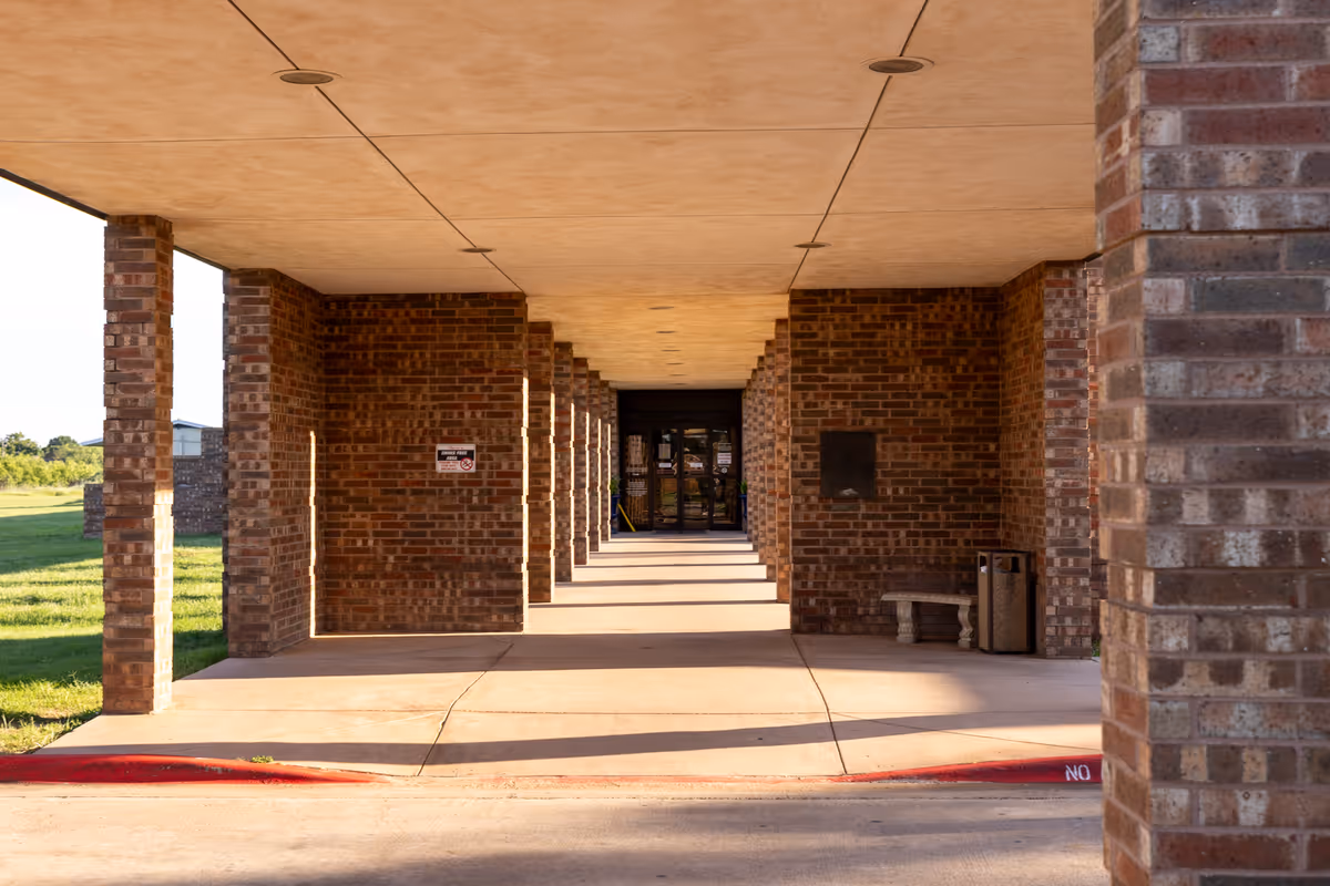 Brick exterior walkway with columns leads to a glass entrance at Mesa Springs Healthcare Center.