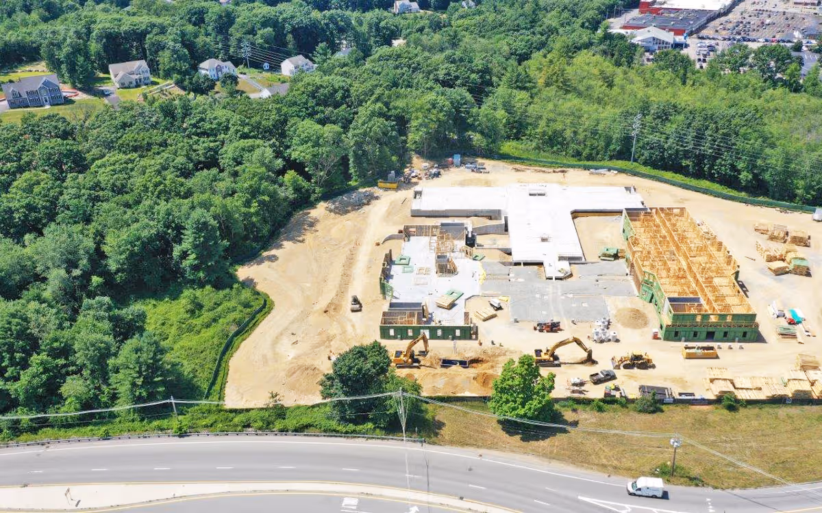 Aerial view of a construction site with a partially built building amid trees.