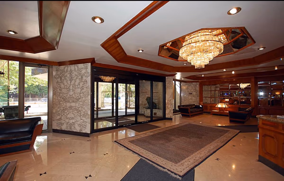 Luxurious lobby with chandelier, marble floor, glass doors, and modern seating for residents.
