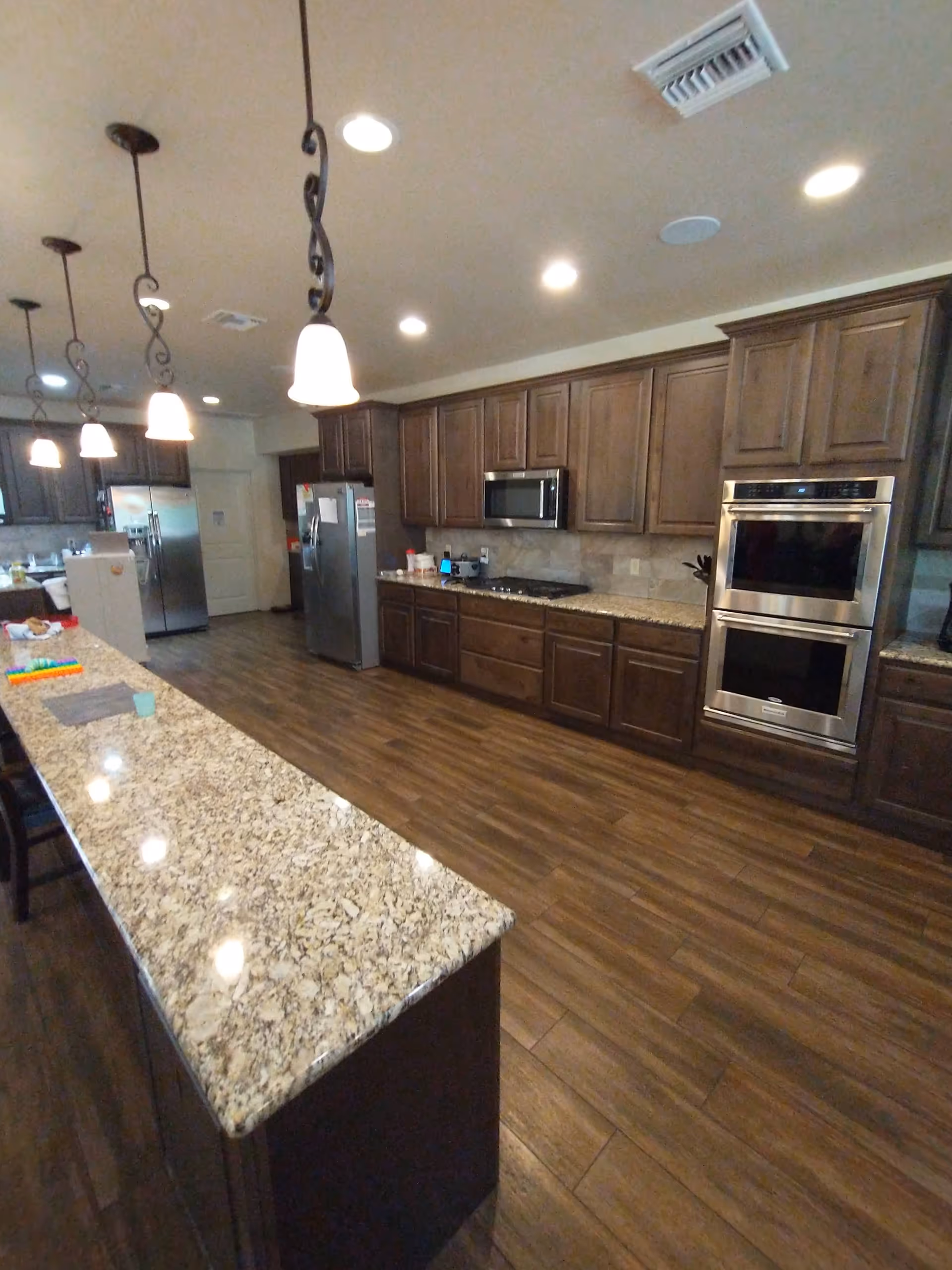 Modern open-plan kitchen with granite countertops, dark wood cabinets, and stainless appliances.