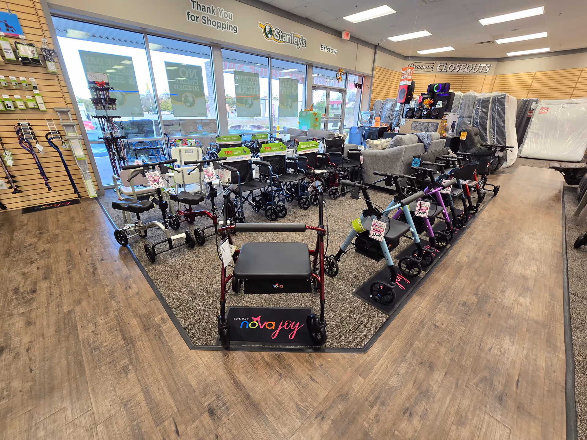 Interior mobility showroom with wheelchairs, walkers, scooters, and display furniture on wooden floors.
