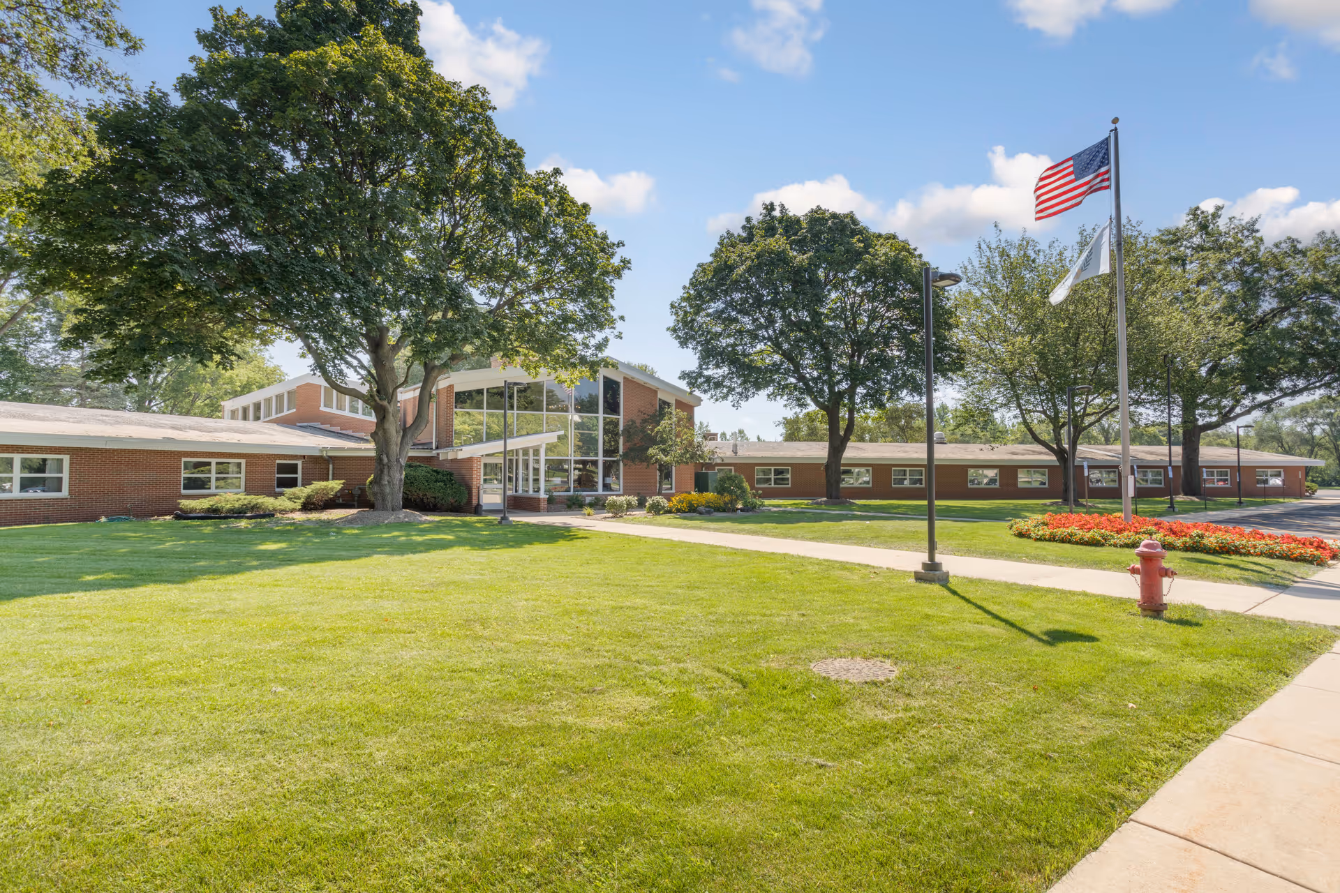 Front view of Alden Debes Rehabilitation & Health Care Center with flagpoles and lawn.